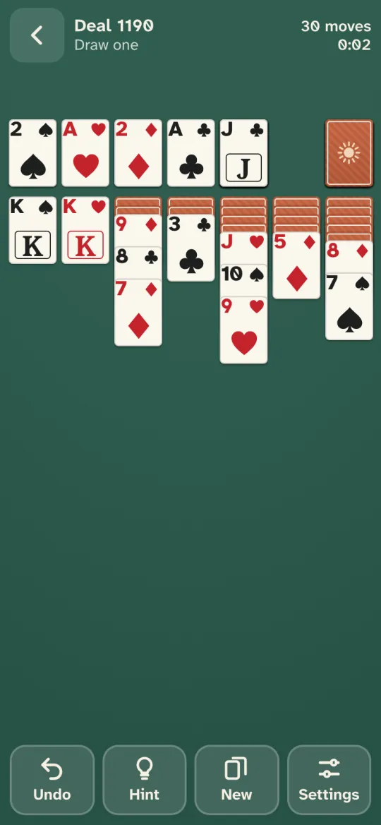 A game of Sunroom Solitaire on the sage green Garden table, ivory cards with large red and black corner numbers fanned in seven columns
